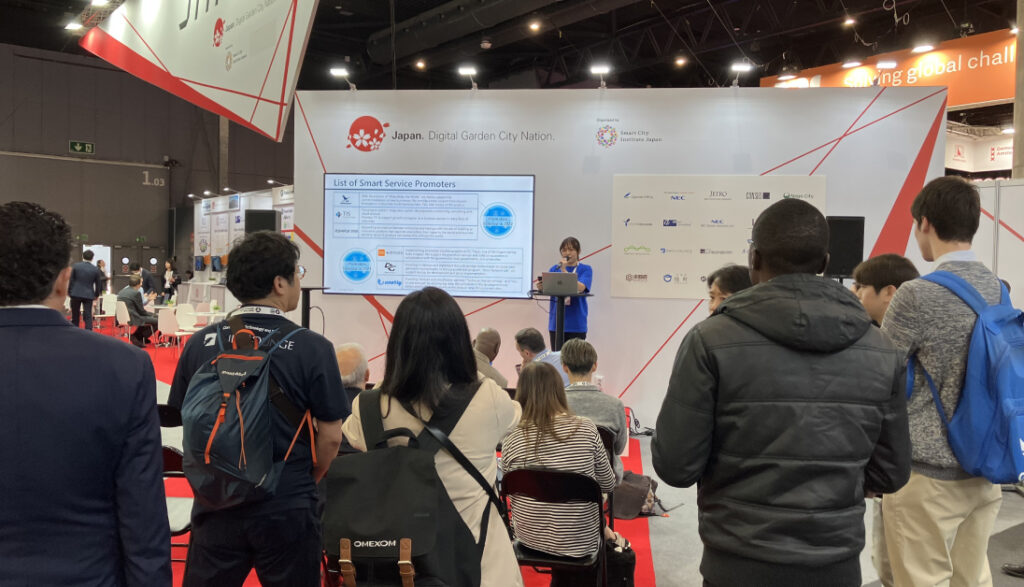 写真:日本パビリオンブースで行われた「Be Smart Tokyo」のPRを聞く来場者