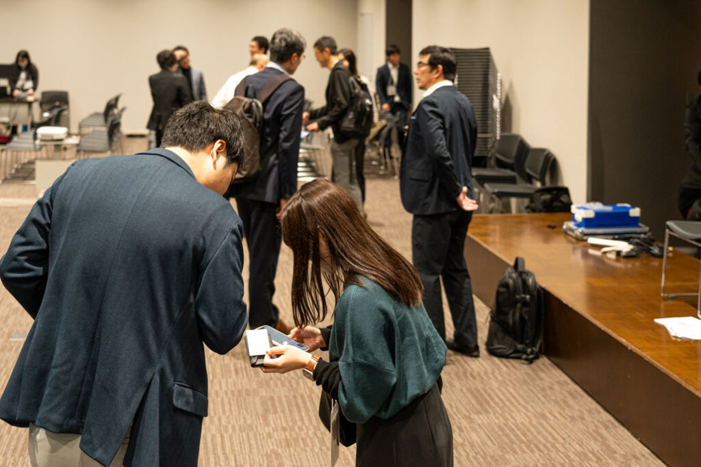 ネットワーキング会の実施時に名刺交換を行っている人々